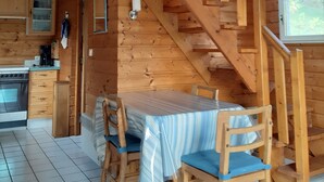 Ein Interieur einer Holzhütte mit Küche, Essbereich und einer Treppe.