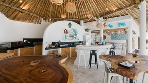 A modern kitchen with a central island, white bar stools, and a rustic wooden table.