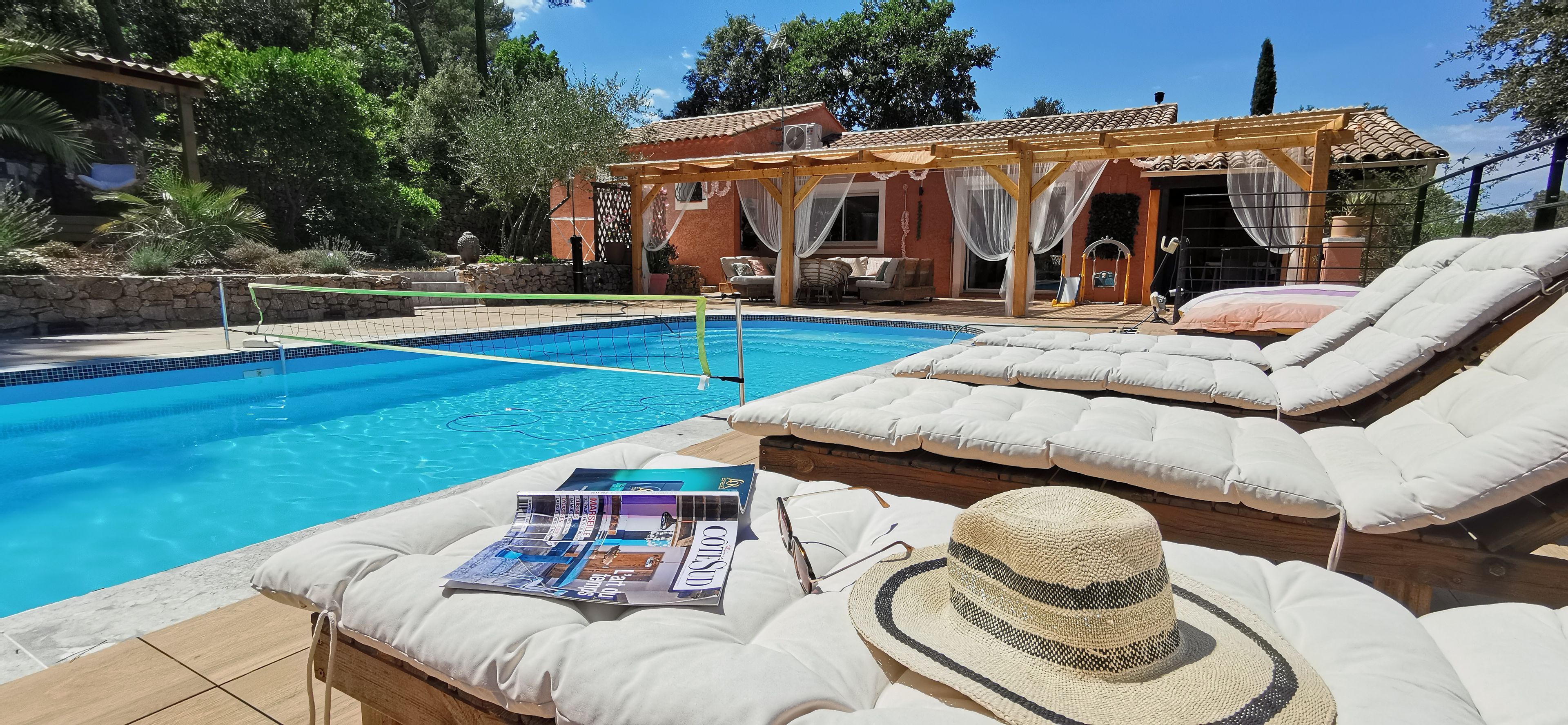 Área de piscina com espreguiçadeiras, uma revista e um chapéu de palha.