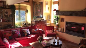 A cozy living room with a red sofa, a small table, and a fireplace. - House, St Rome de Cernon (St Rome de Cernon)