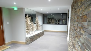 A spacious lobby with a stone wall, a large window, and a decorative wooden tree sculpture. - Wellmaintain sunny 3-room apartment in quiet residence with superb mountain view (Val-D'isère)