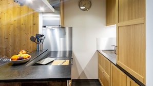 A modern kitchen with wooden cabinets, a stainless steel refrigerator, and a fruit bowl on the counter. - Wellmaintain sunny 3-room apartment in quiet residence with superb mountain view (Val-D'isère)