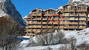 A multi-story wooden lodge with balconies, set against a mountainous backdrop. - Wellmaintain sunny 3-room apartment in quiet residence with superb mountain view (Val-D'isère)