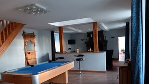Ein Billardtisch in einem Raum mit Holzboden, einer Treppe und einer Bar.