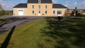Ein zweistöckiges Gebäude mit Garage, befestigter Auffahrt und Rasen mit kleinen weißen Blüten.