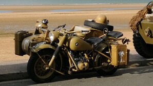 Eine alte Militär-Motorrad mit Beiwagen steht am Strand.