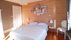 A bedroom with a wooden wall, a bed, two bedside tables, a chair, and a ceiling light.