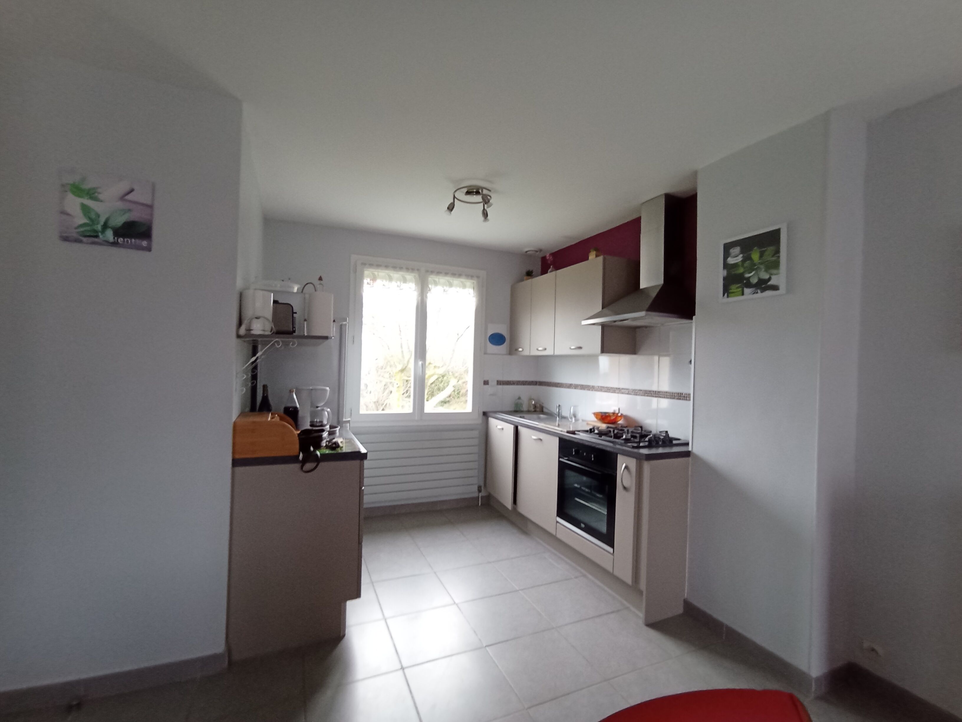A compact kitchen with white cabinets, a gas stove, and a window providing natural light.