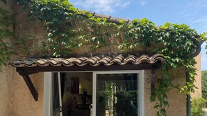 Un patio con tavolo e sedie, un ingresso coperto e vista sull'interno.