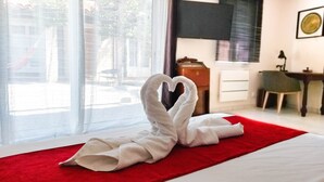 Ein Hotelzimmer mit einem Bett, einer roten Decke und einem Handtuch, das in Herzform auf dem Bett drapiert ist.