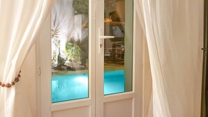 Ein Zimmer mit Glastür zu einem Pool, weißen Vorhängen und einem Bett.