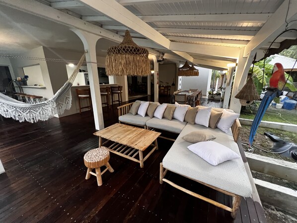 A cozy outdoor seating area with a wooden table, a cushioned sofa, and a hammock.