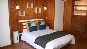 Ein Schlafzimmer mit Holzwandverkleidung, einem Bett, einem weißen Kopfteil und zwei Nachttischlampen.