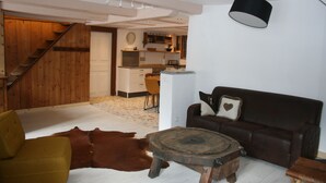 Ein Wohnzimmer mit einem braunen Ledersofa, einem Holztisch, einem gelben Sessel und einem großen braunen Lederteppich.