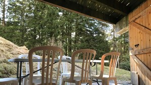 Een houten terras met een tafel en stoelen, omringd door bomen.