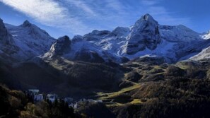 A mountainous landscape with snow-capped peaks and a valley with buildings.