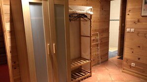 Een houten kamer met een kledingkast, een droogrek en een betegelde vloer.