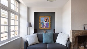 A living room with a dark sofa, a fireplace, and a framed artwork on the wall. - LE CORSAIRE - Petit cocon dans l'Intra-Muros (Saint-Malo)