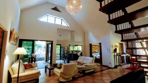 A spacious living area with a high ceiling, a staircase, and a view of the outdoors. - Superb villa with heated swimming pool and jacuzzi in lush greenery (Saint-Pierre)