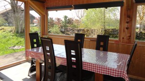 Zona pranzo in legno con tavolo ricoperto da una tovaglia a quadretti, circondato da sedie.