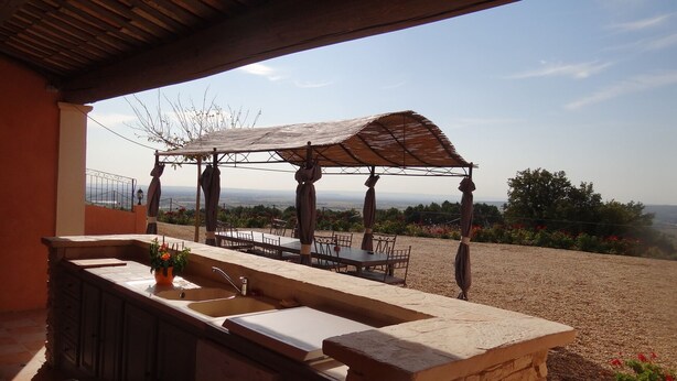An outdoor patio with a stone sink, a wooden table, and a pergola with umbrellas. - Large Mas with heated pool for 10 people, 3 Bathrooms panomaric view (Cairanne)