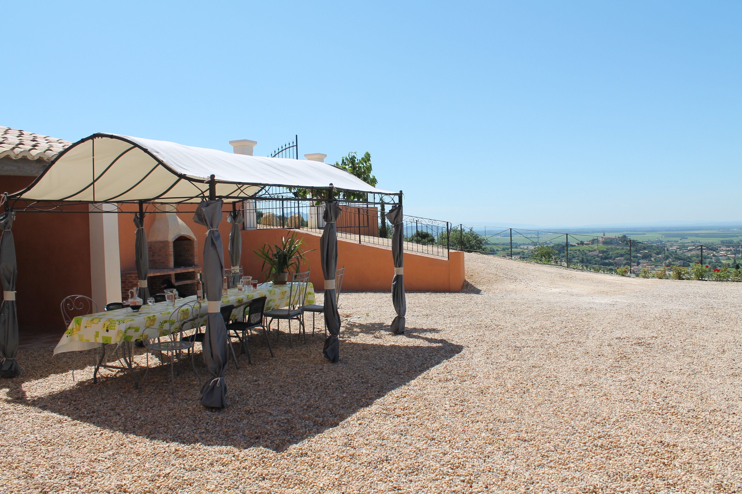 An outdoor dining area with tables and chairs, a covered seating area, and a view of the landscape.