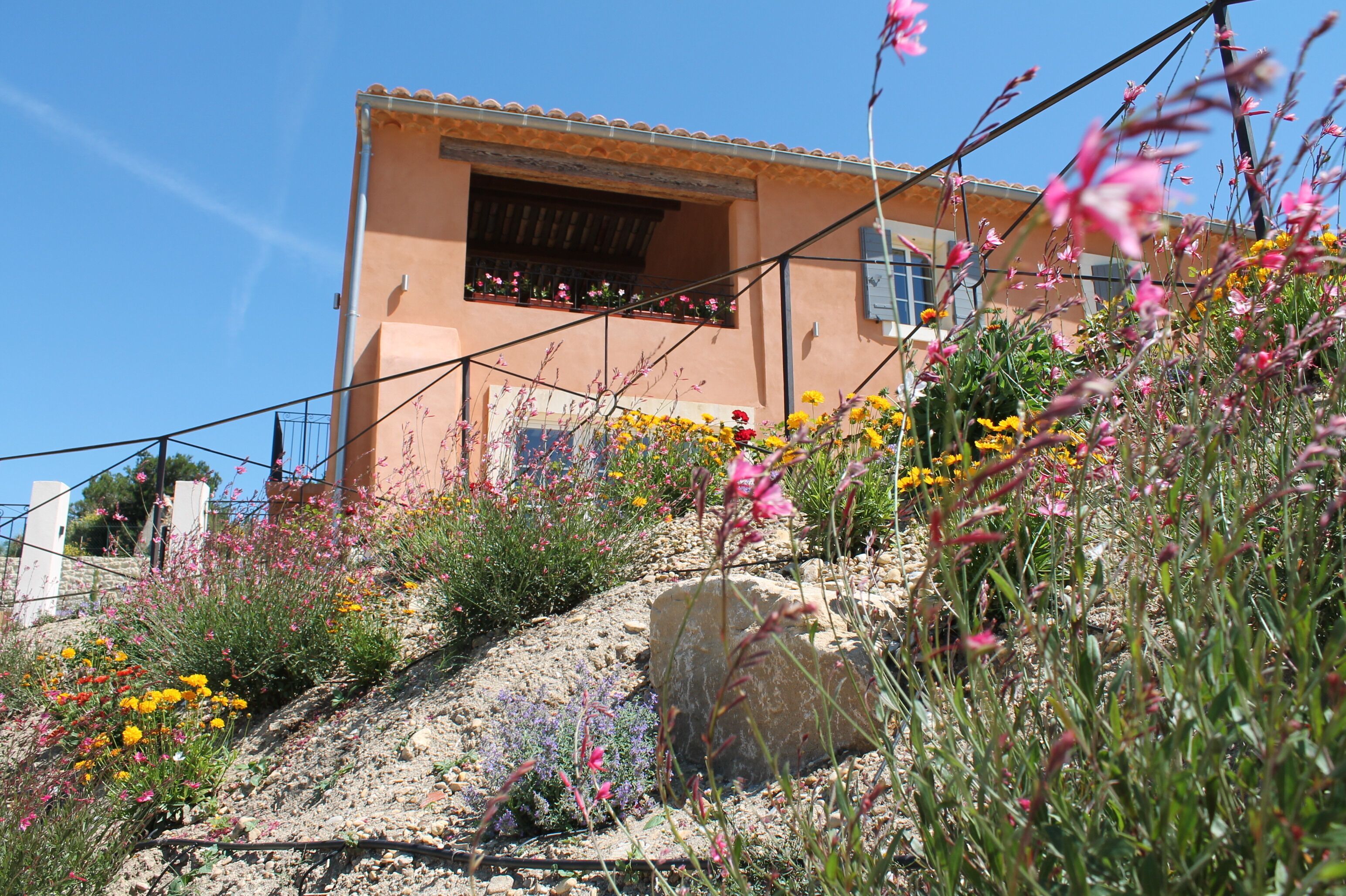 A building with a sloped roof and a balcony with potted plants.