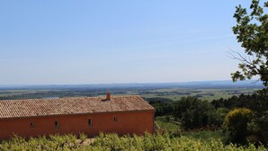 A red building with a tiled roof, surrounded by vineyards and a distant view of fields. - Large Mas with heated pool for 10 people, 3 Bathrooms panomaric view (Cairanne)