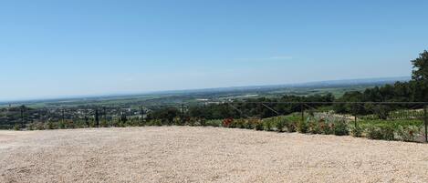 A gravel area with a fence and a view of a distant town.