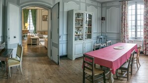 A dining room with a red tablecloth, wooden chairs, and a cabinet with glass doors.