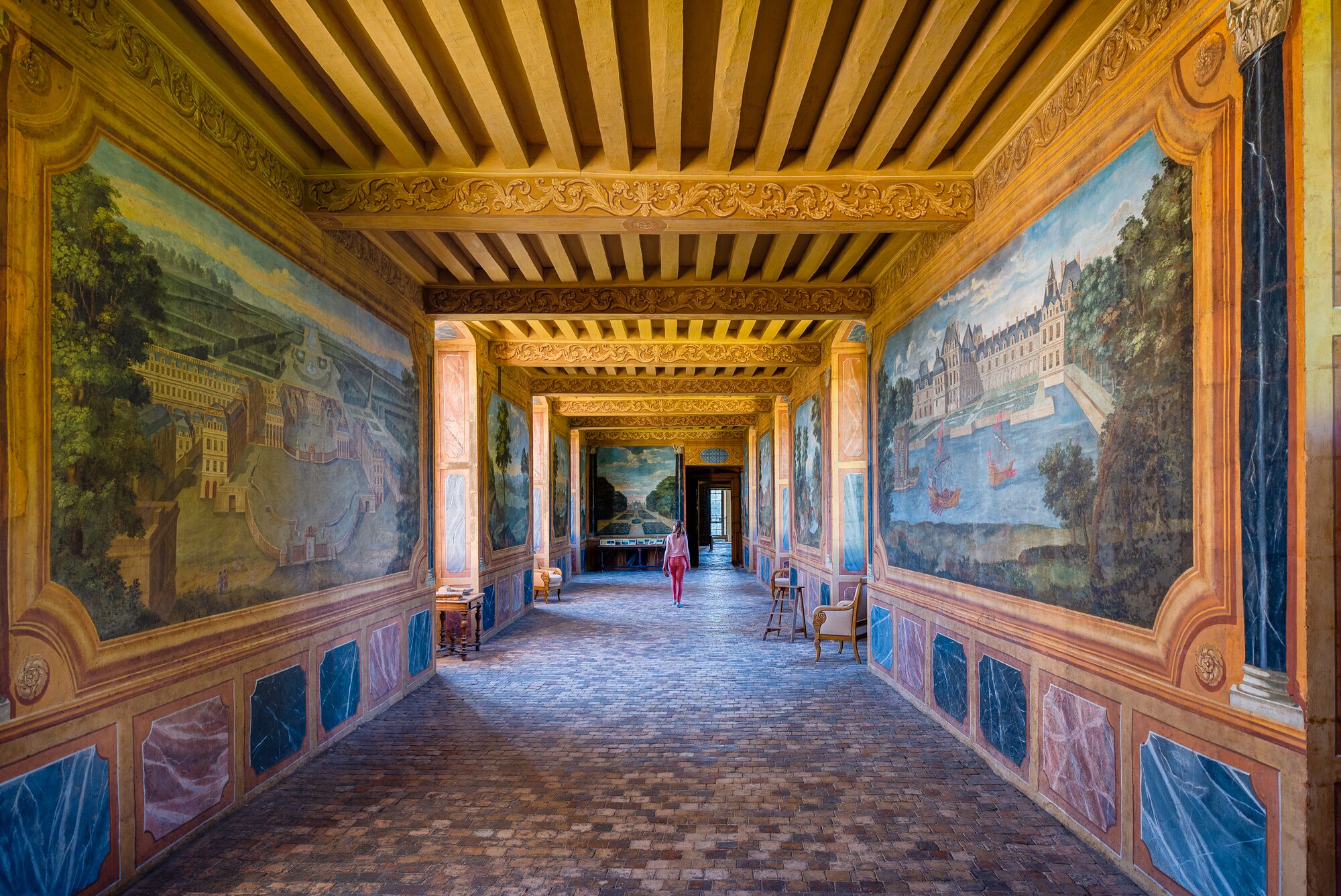 Een statige hal met een gewelfd plafond, versierde zuilen en gedetailleerde fresco's op de muren.