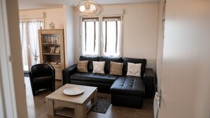Uma sala de estar moderna com um sofá de couro preto, uma mesa de centro de madeira e uma estante.