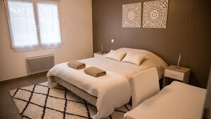 Quarto bem arrumado com cama, duas mesas de cabeceira, um radiador e um tapete estampado.