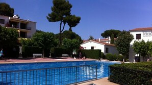 A swimming pool with a tiled deck, surrounded by greenery and buildings. - 5 minutes from the beach, a charming apartment in a beautiful residence.... (CALELLA DE PALAFRUGELL)