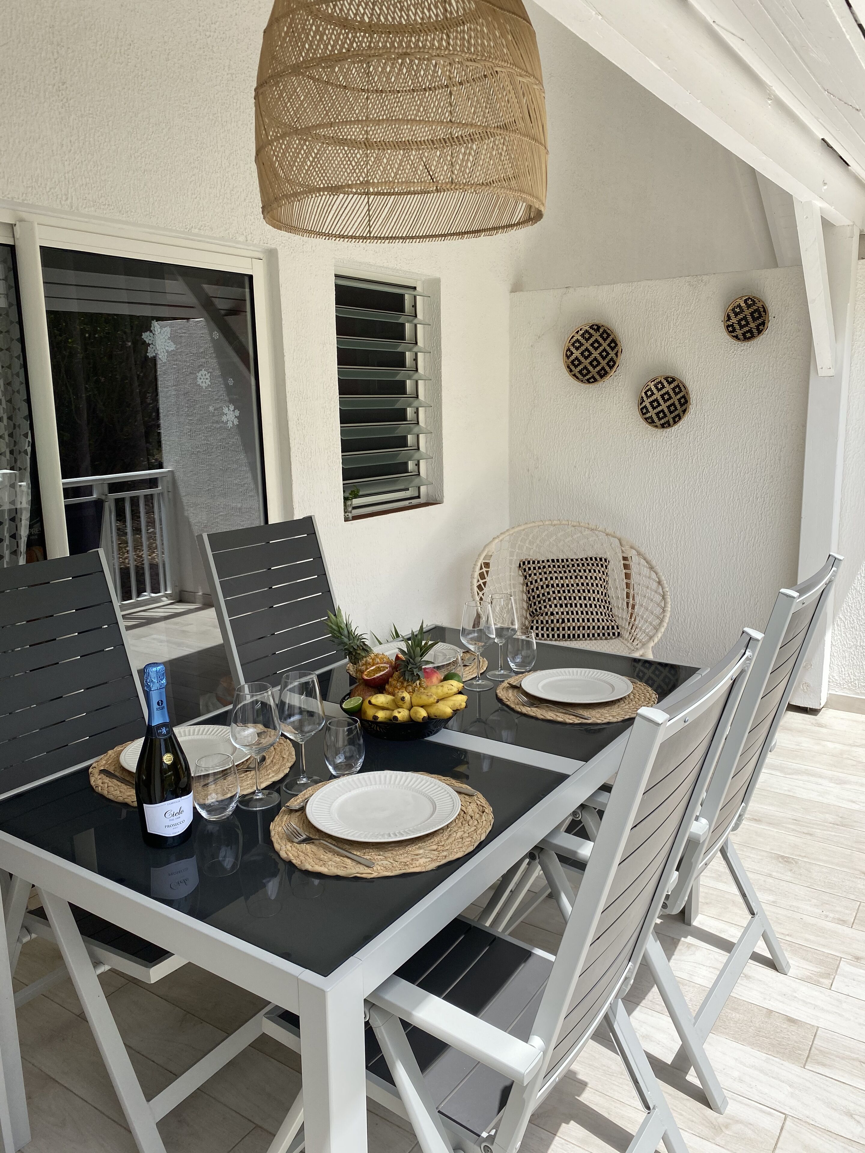 Une table à manger dressée avec des assiettes, une bouteille de vin et un saladier de fruits.