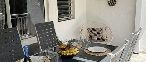 A dining table set with plates, a bottle of wine, and a bowl of fruit.