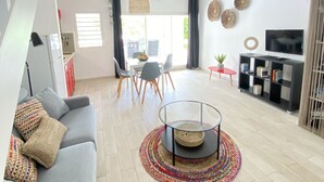 Ett rymligt vardagsrum med en grå soffa, ett runt soffbord i glas och en TV-bänk med böcker och dekorativa föremål.