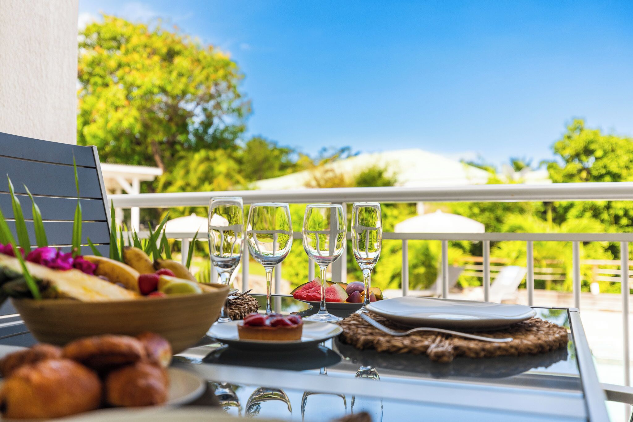 A table set for a meal with a view of lush greenery and a clear sky.