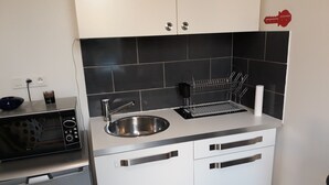 A compact kitchen with a stainless steel sink, a microwave, and a dish rack. - Studio 15m2 seaside (La Seyne-sur-Mer)