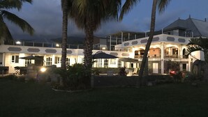 A two-story building with a balcony, outdoor seating area, and a well-lit entrance. - Beautiful apartment on the west coast of Reunion Island - Promo 19/05 to 22/05 (Saint Paul)