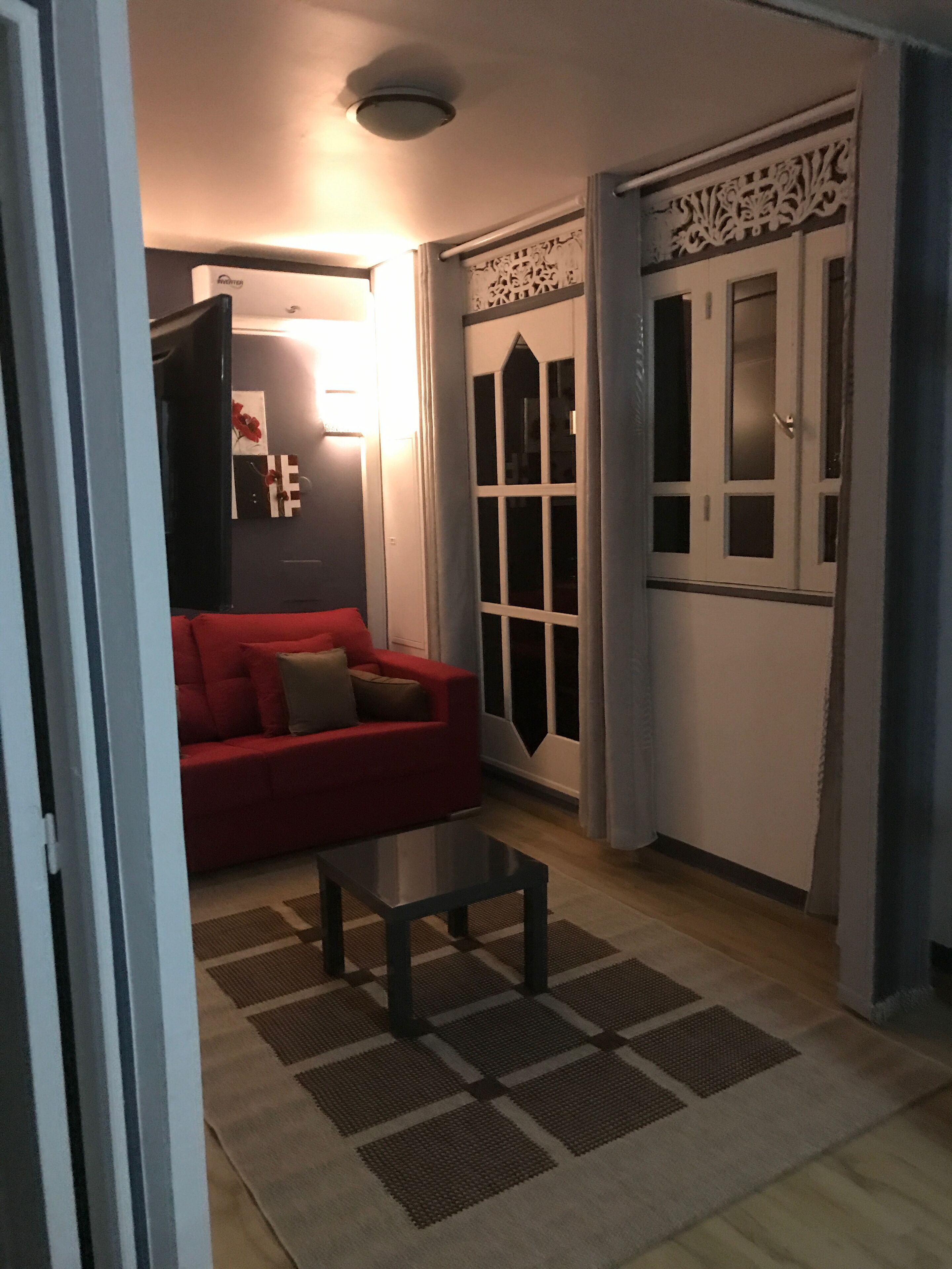 A living room with a red sofa, a glass coffee table, and a patterned rug.