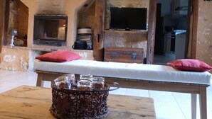 Ein rustikaler Raum mit einer Holzbänkl, einem Kamin, einem Fernseher und einem Tisch mit einem Korb.