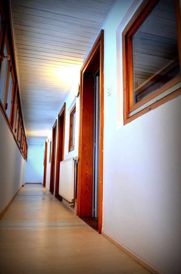 A long, narrow hallway with wooden doors and windows, leading to multiple rooms.