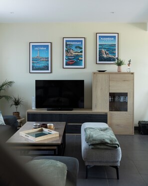 Un salon moderne avec un téléviseur à écran plat, un meuble en bois et trois affiches encadrées accrochées au mur.