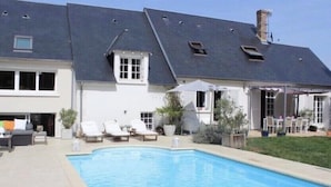 Une maison avec une piscine, un patio couvert et un jardin.