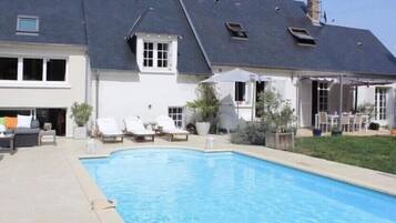Une maison avec une piscine, un patio couvert et un jardin.