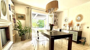 Un espace repas moderne avec une table en bois foncé, des chaises transparentes et un luminaire suspendu.