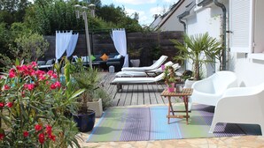 Un espace patio avec une piscine, des chaises longues, une table et des plantes en pot.