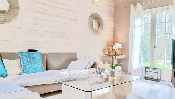 Un salon moderne avec un canapé beige, une table basse en verre et une grande fenêtre.