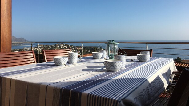 A dining table set with patterned bowls and a lantern on a balcony overlooking the sea. - Superb new apartment, luxury, stunning sea views (Llançà)